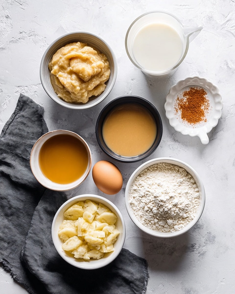 A flat lay of seven small white and black bowls arranged on a white marbled surface, each filled with different ingredients: one bowl contains beige chopped or mashed bananas, another has a light brown smooth liquid, a third bowl holds a golden syrupy liquid, a fourth bowl is filled with a powdery off-white flour, and the fifth bowl contains a crumbly, pale yellow mixture. Nearby, a single brown egg, a small glass of white milk, and a small white dish with a reddish-brown spice sit on a dark gray cloth. The scene is bright and softly lit, with a clean and simple style. photo taken with an iphone --ar 4:5 --v 7