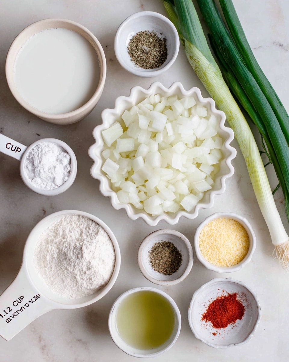 A white table holds several small white bowls and cups with different ingredients. In the center, a ruffled white bowl is full of diced white onions. To the bottom left, a white bowl contains a liquid that looks like milk. Nearby, a white measuring cup marked