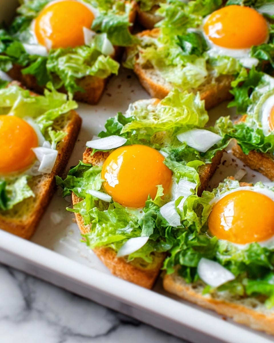 The image shows a white baking dish with several pieces of toasted bread topped with layers. Each piece has a base layer of bread with a textured spread, followed by chopped fresh green leafy lettuce and thin slices of white onion. On top of the greens is a bright orange egg yolk sitting in the middle of each bread piece, adding a smooth, shiny layer that contrasts with the rough texture below. The dish is set on a white marbled surface, and the overall colors are fresh greens, bright orange, and light beige from the bread. Photo taken with an iphone --ar 4:5 --v 7