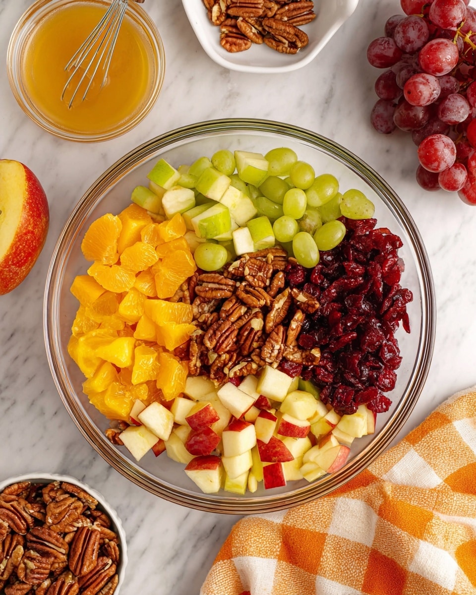 A clear glass bowl filled with six distinct layers of fruit and nuts arranged in sections: bright orange chunks of orange, chopped green apples with pale green skin, whole red grapes, chopped red apples with red skin, dark red dried cranberries in the middle, and a pile of brown pecan halves on top of the grapes and dried fruit. Around the bowl on a white marbled surface are loose pecans, a small bowl filled with pecans, a glass jar containing light golden honey with a whisk inside, a white bowl with red grapes, and an orange and white checkered cloth on the lower right. photo taken with an iphone --ar 4:5 --v 7