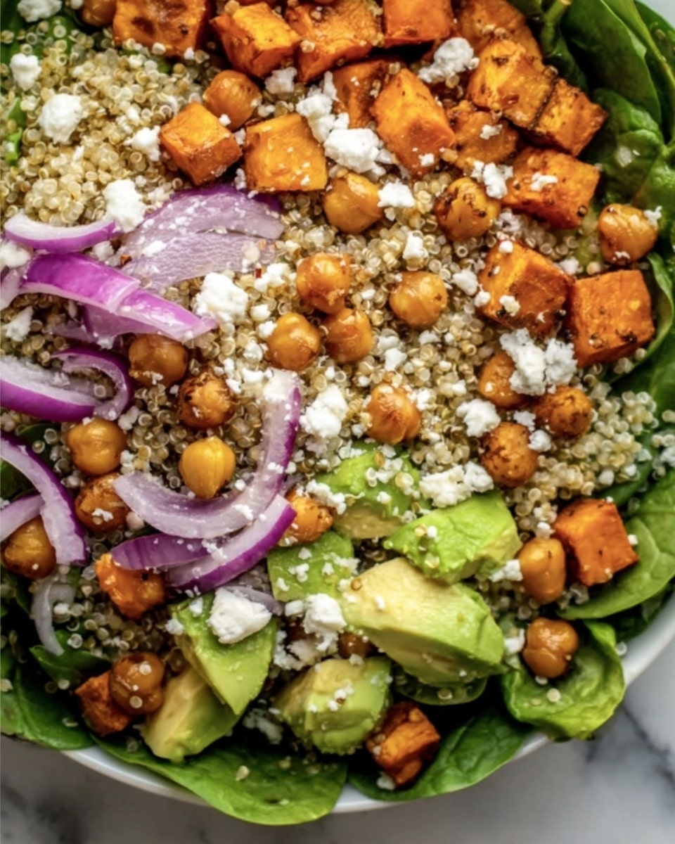 A close-up view of a salad arranged in layers starting with a bed of fresh green spinach leaves at the bottom. On top, there are small cubes of roasted orange sweet potatoes scattered around. Creamy light green avocado chunks appear in clusters throughout the salad. Light brown chickpeas are spread evenly, mixed with small bits of crumbled white cheese. Thin slices of purple-red onion are placed in between the other ingredients. The salad also contains tiny beige quinoa grains sprinkled over everything. The background is a white marbled surface. photo taken with an iphone --ar 4:5 --v 7