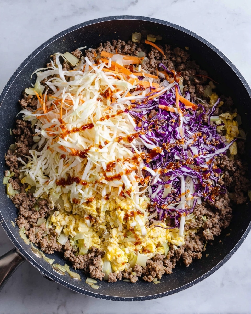 A large black pan holds three main layers of food: the bottom layer is crumbly brown cooked ground meat mixed with small pieces of cooked yellow eggs and translucent chopped onions, the middle layer is a pile of thinly shredded white cabbage with orange carrot strips and purple cabbage mixed throughout, and on top there are small streaks of dark reddish-brown sauce. The pan sits on a white marbled surface. photo taken with an iphone --ar 4:5 --v 7