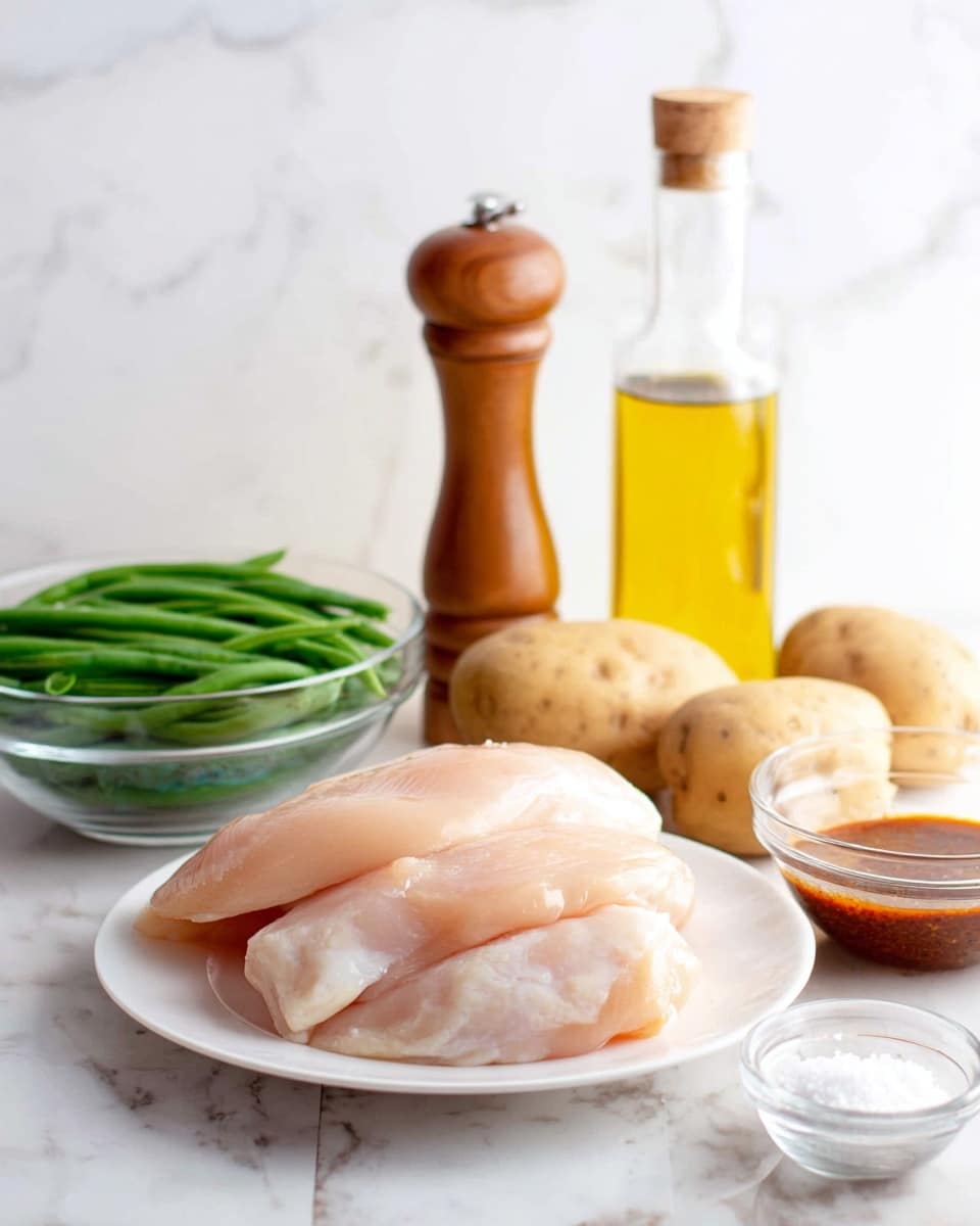 The image shows a collection of fresh cooking ingredients arranged on a white marbled surface. In the center front, there is a white plate with three smooth, pale pink raw chicken pieces stacked. To the left, a clear glass bowl is filled with fresh green beans, bright and firm. Behind the bowl, there are two medium-sized light brown potatoes with a slightly rough texture. To the right of the potatoes, a tall wooden pepper grinder stands with warm brown tones and smooth curves. Next to it is a clear glass bottle filled with golden yellow olive oil. On the far right, a small clear glass bowl contains a dark reddish-brown sauce or marinade with a slightly thick texture. A small glass bowl with white granulated salt is placed near the green beans. The background matches the white marbled surface, creating a bright and clean setting. Photo taken with an iphone --ar 4:5 --v 7