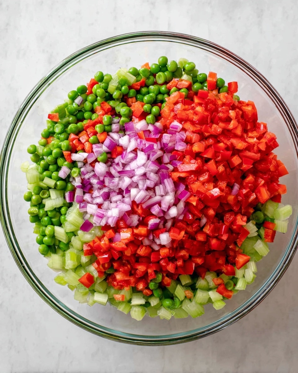 A clear glass bowl is filled with a colorful mixture of finely chopped vegetables. The bottom layer has pale green celery pieces with a crunchy texture. On top of the celery, there is a layer of bright green peas, round and smooth. The top two layers are made up of finely diced red bell peppers and small pieces of purple onion, each adding a vibrant red and purple color and a firm texture. The bowl is placed on a white marbled surface. photo taken with an iphone --ar 4:5 --v 7