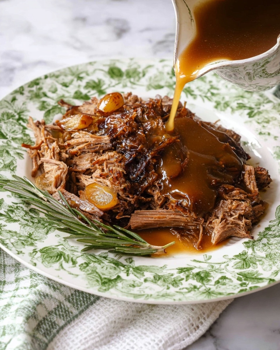 A white plate with a green floral pattern holds a pile of shredded brown cooked meat, with a few whole pearl onions mixed in. A brown gravy is being poured over the meat from the right side, creating a glossy texture and adding a rich and shiny layer on top. A small sprig of green rosemary lies next to the meat on the plate. The plate is placed on a white marbled surface with a white cloth that has a green checkered pattern partly visible. photo taken with an iphone --ar 4:5 --v 7