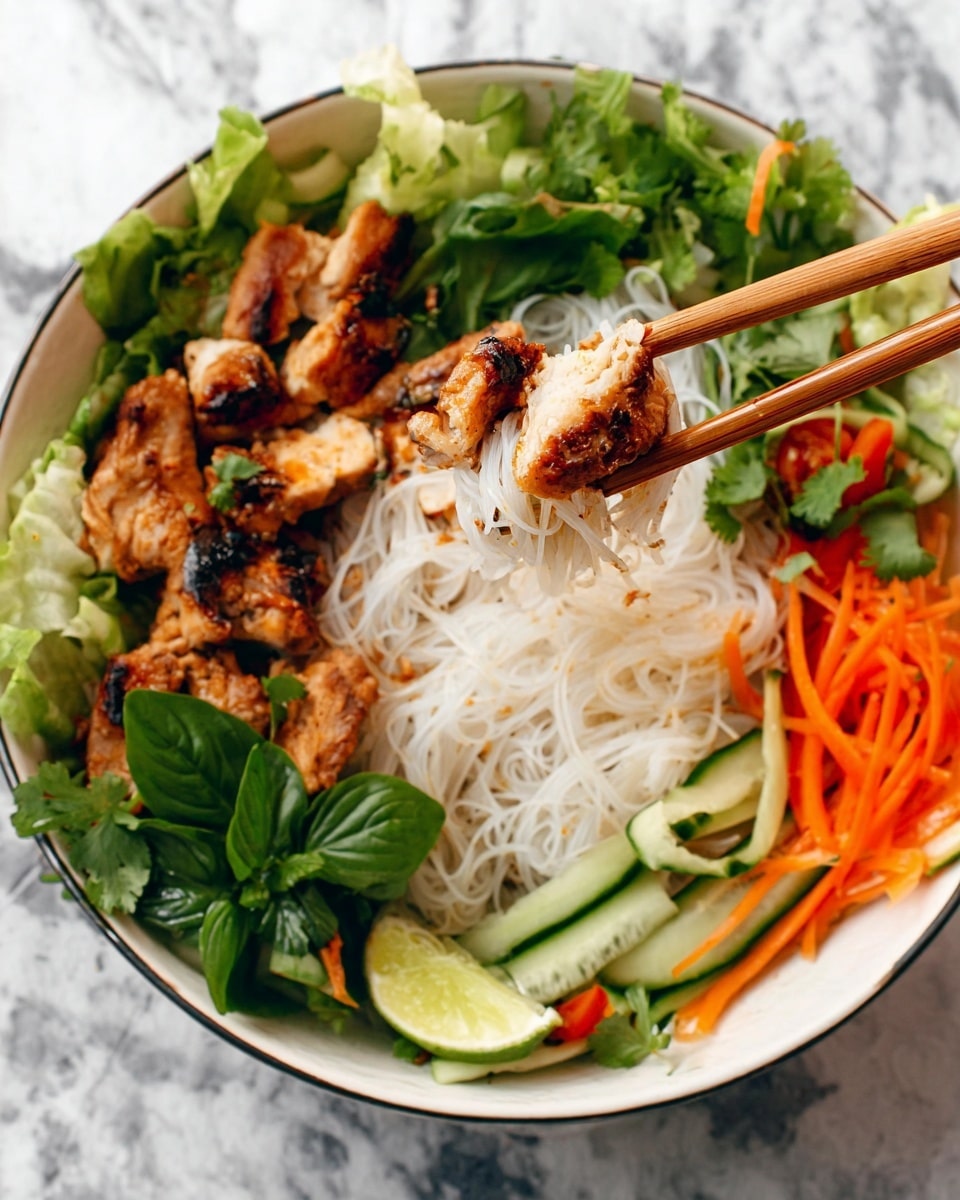 In this image, a white bowl holds a vibrant dish with three main layers. The bottom layer is thin, white rice noodles, soft and slightly tangled, covering most of the bowl's base. On top, there are several pieces of golden-brown grilled chicken with a slightly charred texture, adding a grilled look. Around the noodles and chicken, fresh green leafy herbs and vegetables are placed, including basil leaves, cilantro, and thin strips of orange carrot and green cucumber. A lime wedge peeks from the side, adding a fresh, zesty touch. A pair of wooden chopsticks holds some chicken and noodles above the bowl. The background is a white marbled texture. Photo taken with an iphone --ar 4:5 --v 7