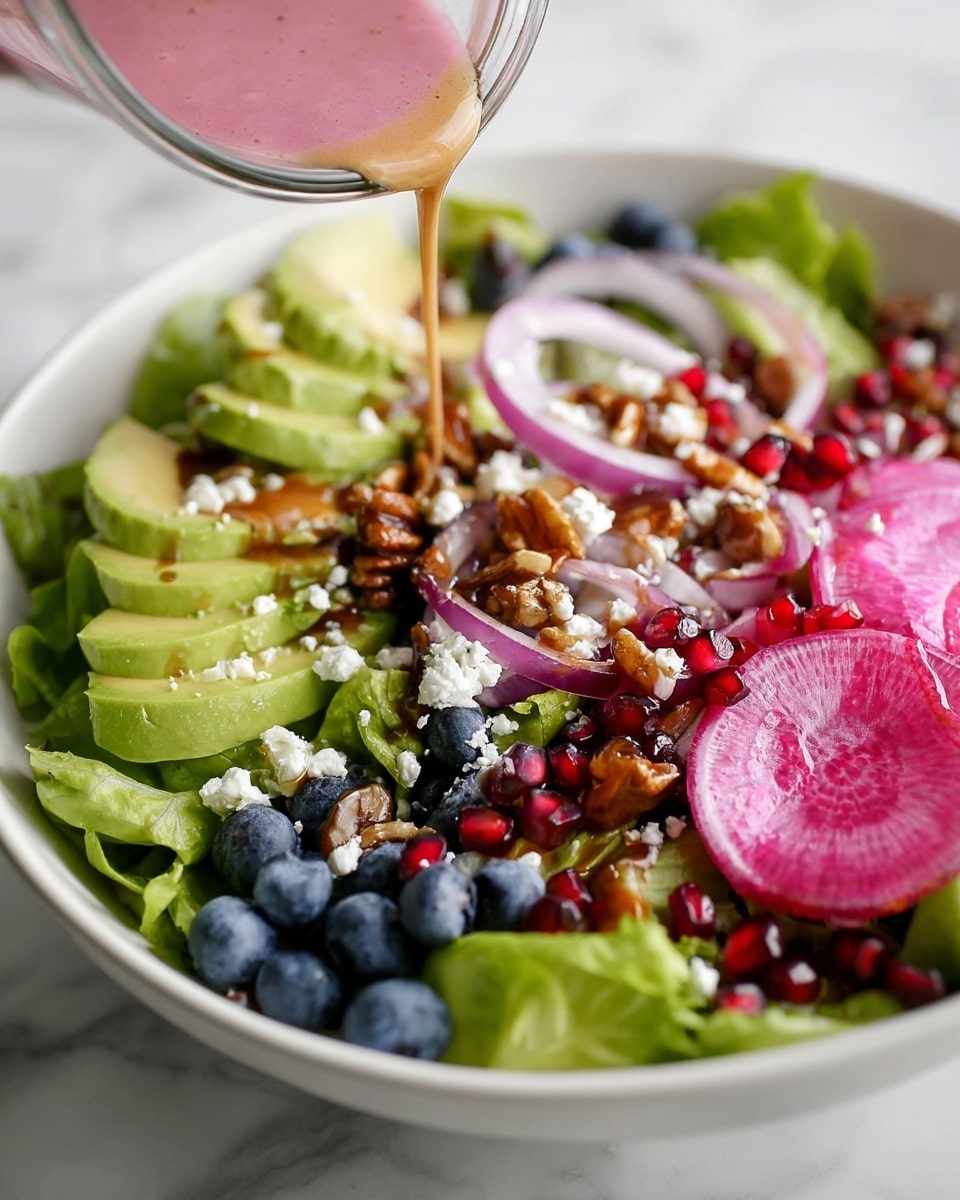 A white bowl filled with green leafy lettuce forms the base layer, topped with thin, round slices of purple and white radish on the right side. There are neatly arranged slices of light green avocado in the center with white crumbled cheese sprinkled on top. Small dark blue blueberries and bright red pomegranate seeds are spread evenly throughout the salad. Thin rings of light purple onion are placed over the vegetables, and glazed nuts with a shiny brown coating add texture. A stream of pink salad dressing is being poured onto the avocado from a clear glass container, with the creamy sauce slightly pooling on the avocado slices. The bowl sits on a white marbled surface. Photo taken with an iphone --ar 4:5 --v 7