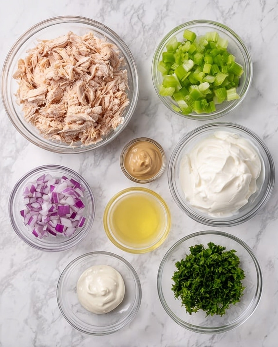 There are seven clear glass bowls arranged on a white marbled surface. The largest bowl at the top left is filled with light pink shredded cooked chicken. To the right, a medium bowl contains small chopped green celery pieces. Next, another medium bowl holds thick white sour cream. Below the chicken, a small bowl has smooth beige mustard. In the center, a small bowl contains pale yellow lemon juice. To the left of the lemon juice, a small bowl has finely chopped purple-red onions. Lastly, at the bottom right, a small bowl holds finely chopped green herbs. photo taken with an iphone --ar 4:5 --v 7
