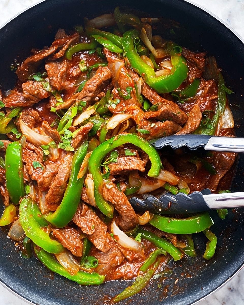This image shows a pan full of stir-fried beef strips with green bell pepper slices and white onion pieces mixed in a rich, reddish-brown sauce. The beef pieces are thin and tender, spread evenly throughout the dish, while the green bell peppers add bright green curved shapes on top. The onion slices are translucent white and are scattered, adding light color contrast. Fresh green herbs are sprinkled over the dish, adding specks of vibrant green. A pair of black tongs with silver handles rests inside the pan, slightly lifting some of the ingredients. The pan's black interior contrasts with the colorful food. The background is a white marbled texture. photo taken with an iphone --ar 4:5 --v 7