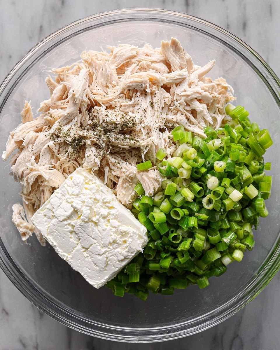 A clear glass bowl on a white marbled surface contains three main layers: on the left, shredded light beige chicken with some black pepper sprinkled on top; on the right, a heap of chopped bright green spring onions; and in the center, a white block of cream cheese with a slightly smooth texture. The ingredients are separate and clearly visible, ready to be mixed. photo taken with an iphone --ar 4:5 --v 7