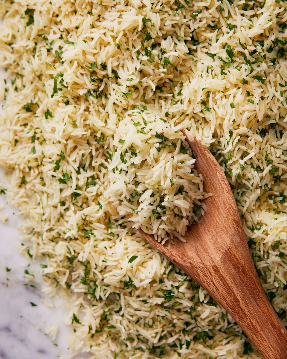 The image shows a large amount of cooked rice mixed with small green herb pieces, likely parsley or cilantro, spread out over a white marbled surface. The rice grains are long and slightly yellowish with a fluffy texture, mixed evenly with the finely chopped green herbs. A smooth, light brown wooden spoon scoops up some of the rice from the surface, with the spoon positioned towards the right side of the image, showing the curved shape and fine wood grain. photo taken with an iphone --ar 4:5 --v 7
