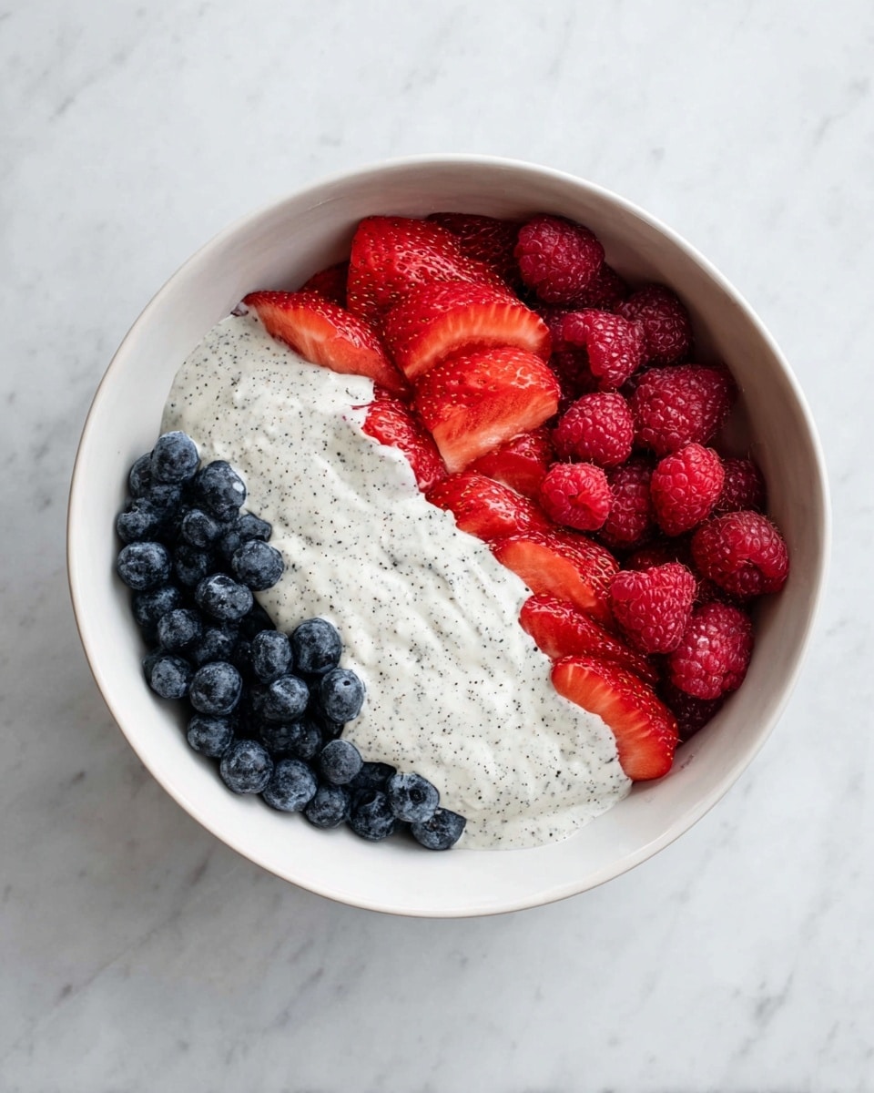 In a white bowl, there are three main layers arranged side by side: bright red sliced strawberries on the left, deep red raspberries in the middle, and dark blue blueberries on the right. Over the middle section, a creamy white sauce with black specks is spread, covering parts of the raspberries and the blueberries. The bowl sits on a white marbled surface. photo taken with an iphone --ar 4:5 --v 7