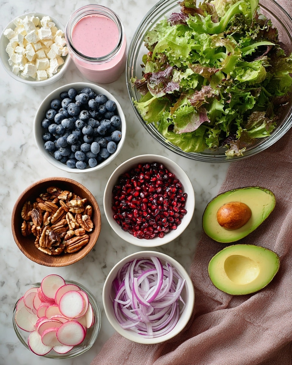 A big clear glass bowl of mixed green leafy lettuce sits at the top on a white marbled surface. Below it, from left to right, there is a white bowl filled with fresh blueberries, a wooden bowl with glazed nuts, a white bowl of red pomegranate seeds, and to the right side, two halves of avocado with seed in one half and empty in the other, resting on a dusty pink cloth. At the bottom of the image are a white bowl of thinly sliced purple onion, a smaller white bowl of crumbly white cheese, and a white bowl with round pink and light green radish slices. To the top left of the bowls, a small glass jar of pink creamy dressing is visible. Photo taken with an iphone --ar 4:5 --v 7