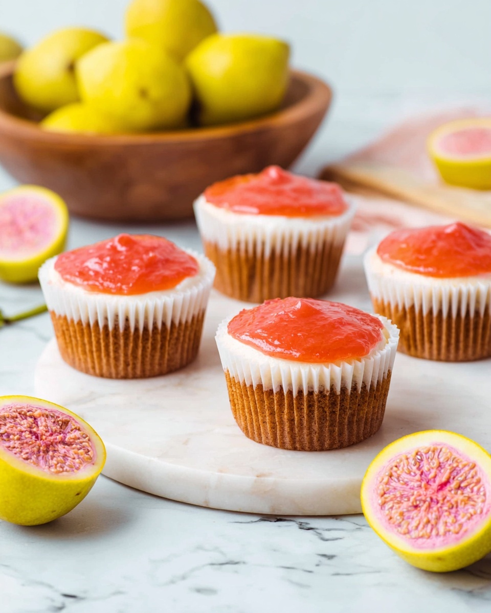 Four cupcakes are shown on a white marbled round board. Each cupcake has three layers: a light brown base, a middle layer of white frosting, and a shiny, smooth red-orange topping. The cupcakes are wrapped in white baking cups. Around the board, there are whole and halved yellow guavas with pink insides, and a wooden bowl filled with more yellow guavas is visible in the background. The scene is bright and clean with soft lighting. Photo taken with an iphone --ar 4:5 --v 7