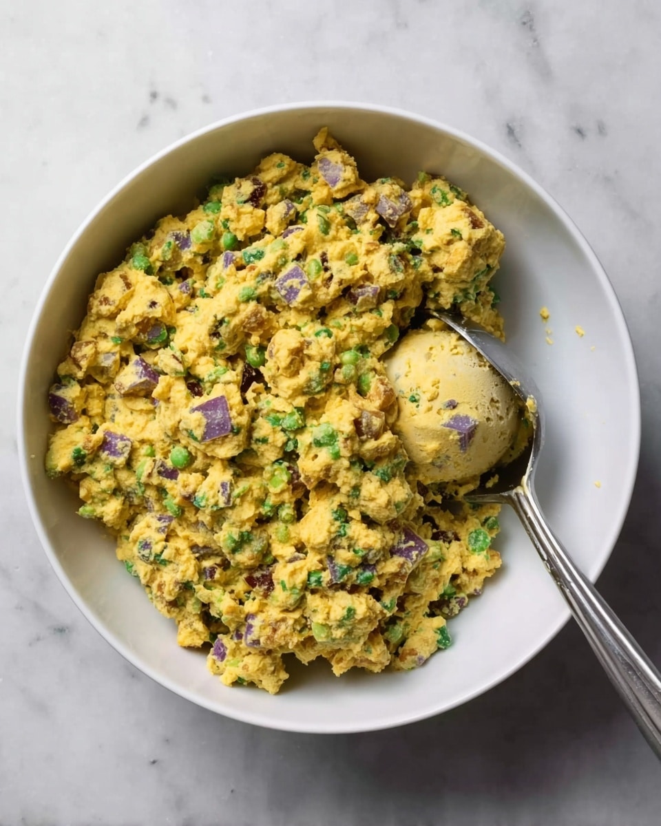 The image shows two slices of dark toasted bread side by side on a white marbled surface, each topped with a thick layer of yellow chickpea salad mixed with bright green chopped celery and scallions, as well as small pieces of purple onion. The chickpea salad looks chunky and moist, generously covering the whole surface of the toast in uneven mounds. The contrast between the dark toast and the vibrant yellow and green salad makes the dish look fresh and hearty. Photo taken with an iphone --ar 4:5 --v 7