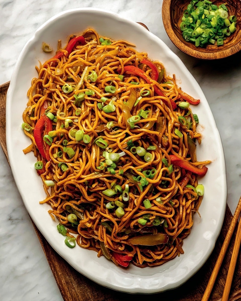 A close-up view of a black pan filled with stir-fried noodles, showing many twisted, golden-brown noodles mixed with soft, translucent white onion slices and thin red bell pepper strips scattered evenly throughout. The pan is placed on a white marbled surface, and the shiny metal handle of the pan is visible on the left side. The noodles have a slightly glossy texture from the sauce and look well-cooked and intertwined, filling the entire pan. Photo taken with an iphone --ar 4:5 --v 7
