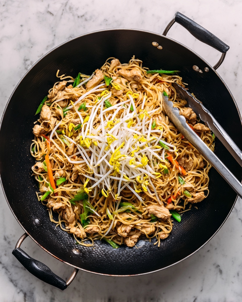 A black wok filled with a stir-fry of brown noodles as the base layer, mixed with small pieces of light brown cooked chicken and thin strands of bright orange carrot and green celery scattered throughout. On top of everything, a bunch of white bean sprouts with yellow tips are spread in the center. Metal tongs with black grips rest on the right side of the wok. The wok is placed on a white marbled surface photo taken with an iphone --ar 4:5 --v 7