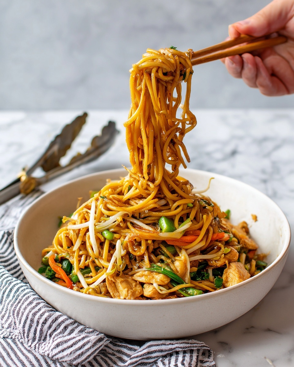 A white bowl filled with a heap of stir-fried noodles sits on a white marbled surface. The bottom layer in the bowl shows pieces of green celery and chunks of light-colored cooked chicken. Above this, there are orange carrot strips and white bean sprouts scattered throughout. The top layer is the shiny brown noodles wrapped around a pair of wooden chopsticks held by a woman's hand, lifting the noodles above the bowl. In the background, metal tongs with bits of food rest on the white marbled surface. A striped cloth lies partly under the bowl. photo taken with an iphone --ar 4:5 --v 7