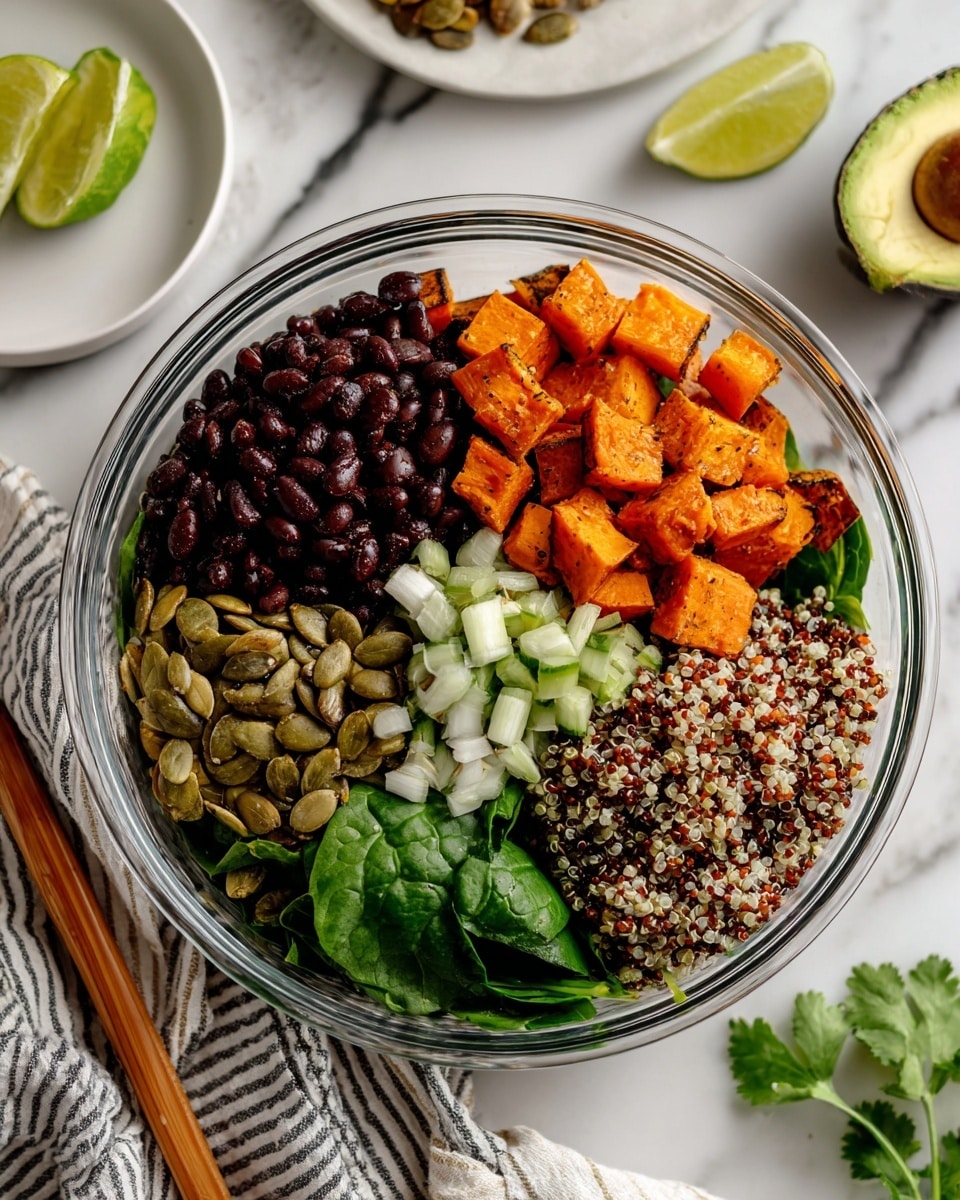 A clear glass bowl holds a colorful layered salad placed on a white marbled surface with a striped cloth and wooden chopsticks nearby. Inside the bowl, there are six distinct layers arranged side by side: dark red-black beans on the left, bright orange roasted sweet potato cubes at the top, light green sliced scallions next to the sweet potatoes, a mix of white, red, and black quinoa grains on the right, fresh green spinach leaves at the bottom left, roasted pumpkin seeds in the middle, and fresh green cilantro leaves scattered over the pumpkin seeds and scallions. In the background, half an avocado and lime wedges sit on a small white plate. Photo taken with an iphone --ar 4:5 --v 7