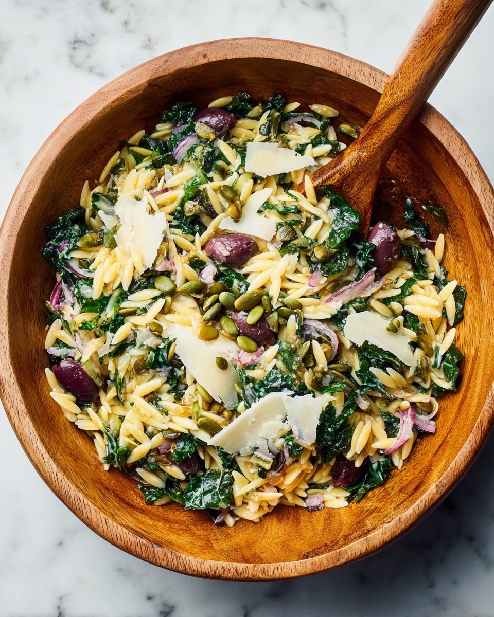 A wooden bowl filled with a mixed salad featuring layered textures and colors. The base layer consists of light yellow orzo pasta grains scattered evenly throughout. Mixed in are dark green leafy vegetables, possibly kale or spinach, which are chopped finely and spread evenly across the salad. Deep purple olives add pops of color throughout the bowl. Topping the salad are medium-sized, thin white cheese shavings scattered randomly. Small green pumpkin seeds are sprinkled over the top, giving a contrasting texture. A wooden spoon is partially visible in the bowl. The bowl sits on a white marbled surface. photo taken with an iphone --ar 4:5 --v 7