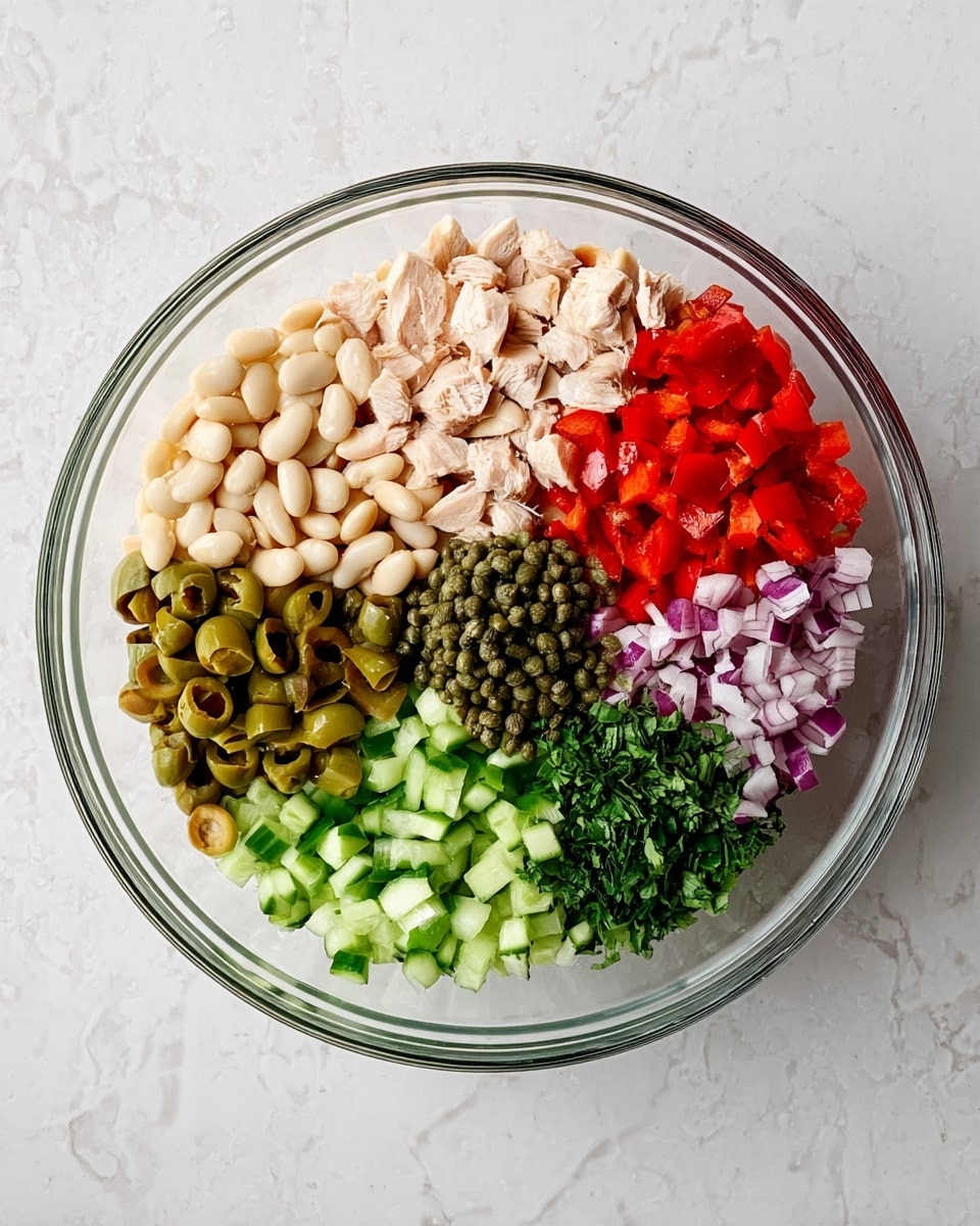 A clear glass bowl sits on a white marbled surface, filled with seven layers of colorful ingredients arranged in neat sections. From the top left clockwise, there are pale beige white beans, bright green cucumber cubes, green sliced olives, bright red diced bell peppers, finely chopped purple onions, light beige pieces of cooked chicken, and green capers centered above the chicken. In the middle, there is a small pile of finely chopped fresh green herbs. The textures range from smooth beans and chicken to crisp cucumbers and peppers, creating a vibrant and fresh look. Photo taken with an iphone --ar 4:5 --v 7
