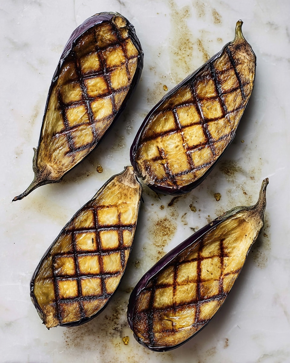 The image shows four halves of grilled eggplants placed on a white marbled surface. Each eggplant half has a dark purple outer skin and golden-brown interior flesh with a slightly charred texture. They are scored with a diamond pattern across the flesh, which shows a range of colors from light yellow to deep brown from grilling, with some areas nearly blackened. The surface around them has scattered oil drops and some light browning marks. Photo taken with an iphone --ar 4:5 --v 7