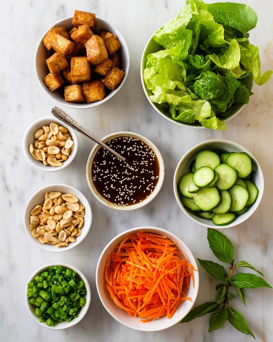 The image shows seven small white bowls arranged on a white marbled surface. The top left bowl contains golden brown fried tofu cubes with a slightly crispy texture. To its right is a bowl filled with bright green fresh lettuce leaves, torn into medium pieces. Below the tofu is a bowl of thin, shredded bright orange carrots, with a slightly crunchy appearance. To the right of the carrots is a bowl of cucumber slices, light green with darker green edges, cut into thin semicircles and stacked loosely. Centered below these bowls is a bowl of dark brown sauce, sprinkled with white sesame seeds, with a spoon resting in it. Below the sauce and to the left is a small bowl of chopped green onions, rich leaf green in color, chopped finely. To the right of the green onions, the last bowl holds a handful of light tan peanuts with a slightly rough texture. A small sprig of green basil leaves rests next to the green onions. photo taken with an iphone --ar 4:5 --v 7