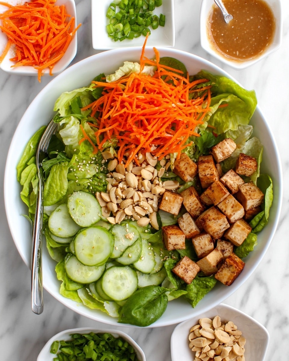 A white bowl filled with crisp green lettuce leaves as the base layer, topped with bright orange shredded carrots on one side, fresh light green cucumber slices arranged neatly next to them, and a pile of light brown tofu cubes that have a slightly browned texture on the other side. Scattered on top are light beige peanuts and small pieces of green onion adding contrast. Around the bowl, there are small white dishes holding chopped green onions, a sesame seed sauce, extra shredded carrots, and more peanuts, all placed on a white marbled surface. A woman's hand holds the bowl steady with a silver fork resting on the bowl’s edge photo taken with an iphone --ar 4:5 --v 7