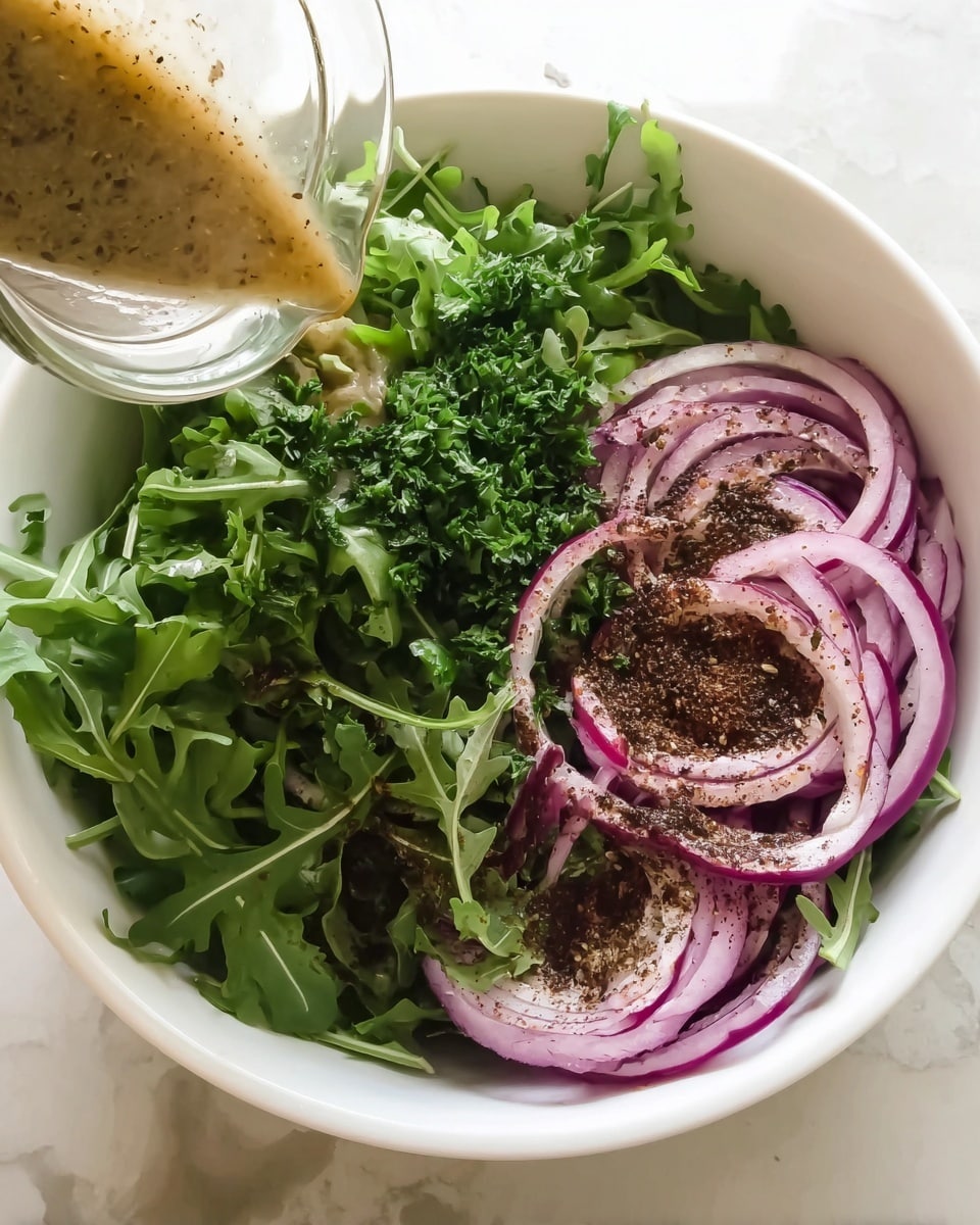 A white bowl filled with fresh green leaves of arugula and finely chopped parsley on one side, and sliced purple-red onion rings sprinkled with dark brown spice on the other side, with a clear glass container pouring a light brown dressing over the onions. The bowl sits on a white marbled surface. photo taken with an iphone --ar 4:5 --v 7