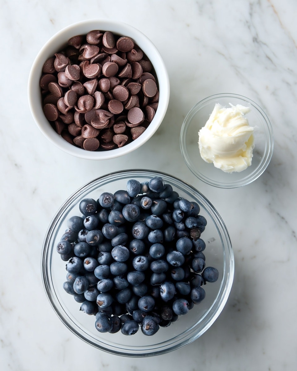 The image shows three bowls on a white marbled surface. The top left bowl is white and filled with dark brown chocolate chips that have a smooth and slightly glossy texture. To the right of it is a small clear glass bowl with a small scoop of white coconut oil, which looks soft and creamy. At the bottom, a larger clear glass bowl holds a large bunch of fresh blueberries, which are deep blue with a matte finish and natural texture. The arrangement is simple and clean, showing contrasting colors and textures clearly. photo taken with an iphone --ar 4:5 --v 7