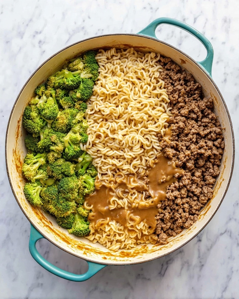 A large white pot with teal handles sits on a white marbled surface, filled with three main layers of food arranged side by side. On the left, there are bright green broccoli florets peeking out from underneath the other ingredients. Next to the broccoli is a pile of light yellow cooked noodles with a soft, curly texture. On the right side, there is cooked brown ground beef with a crumbly texture mixed with some broccoli. In the middle, covering parts of both the noodles and beef, is a spread of thick, light brown sauce that partially coats the noodles, adding a glossy look. The inside of the pot is slightly stained from cooking, contrasting with its clean outer rims. photo taken with an iphone --ar 4:5 --v 7